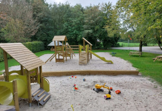 Speeltuin met zandbak en houten speeltoestellen bij Camping de Beukenhof in Drenthe, Nederland.