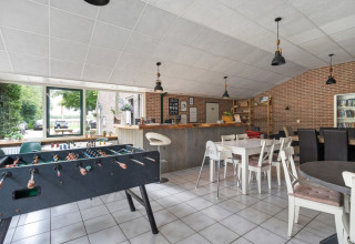 Sala común recreativa en Camping de Beukenhof con futbolín, bar, mesas y sillas en Drenthe, Países Bajos.