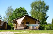 Safari tent Villatent Outback with hammock at Camping de Schatberg in the Netherlands, amidst green trees.
