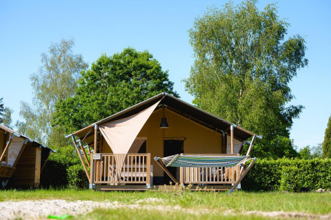 Safari-Zelt Villatent Outback mit Hängematte auf Camping de Schatberg in den Niederlanden, umgeben von Bäumen.
