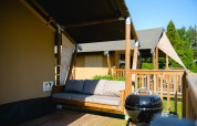 Safari tent Villatent Outback with wooden deck, sofa and BBQ at Camping de Schatberg in the Netherlands.