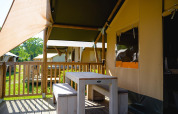 Außenbereich mit Tisch und Bänken vor dem Villatent Outback Safari-Zelt auf Camping de Schatberg, Niederlande.