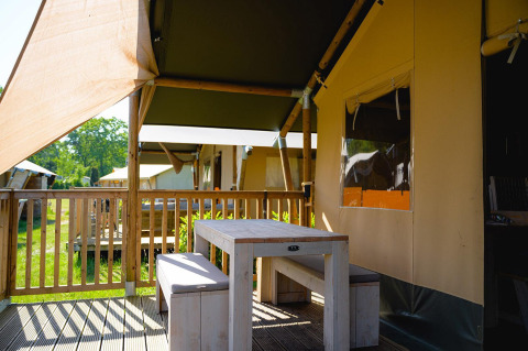Área exterior con mesa y bancos en la tienda safari Villatent Outback en Camping de Schatberg, Países Bajos.