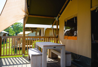 Área exterior con mesa y bancos en la tienda safari Villatent Outback en Camping de Schatberg, Países Bajos.