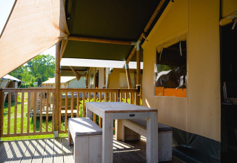 Outdoor dining area with table and benches at the Villatent Outback safari tent at Camping de Schatberg, Netherlands.