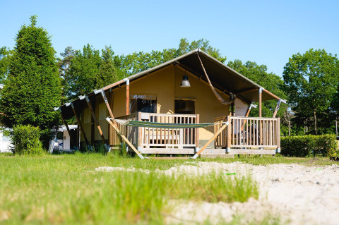 Tienda safari Villatent Outback en Camping de Schatberg en los Países Bajos, rodeada de árboles y césped.