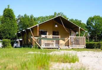 Safaritent Villatent Outback op Camping de Schatberg in Nederland, omgeven door gras en groene bomen.