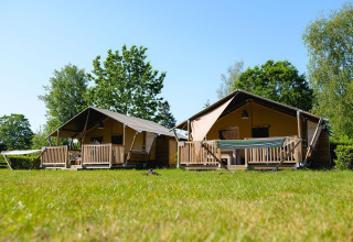 Twee Villatent Outback safaritenten op Camping de Schatberg in Nederland, omringd door gras en bomen.