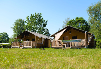 Two Villatent Outback safari tents at Camping de Schatberg in the Netherlands, surrounded by greenery.