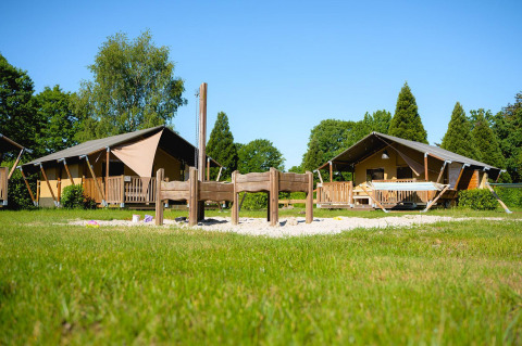 Safaritenten op Villatent Outback bij Camping de Schatberg in Nederland met groen gras en speelgedeelte.