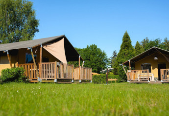 Tende safari con veranda in legno sull’erba verde a Villatent Outback, Camping de Schatberg, Olanda.