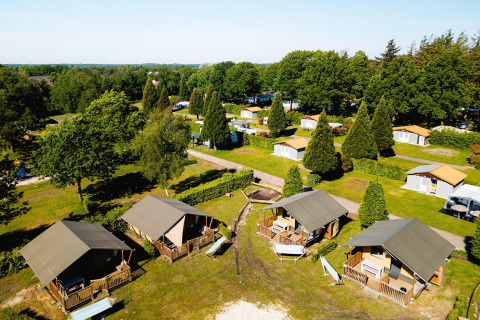 Luchtfoto van safari tenten Villatent Outback en kampeerplaatsen omringd door groen op Camping de Schatberg, Nederland.