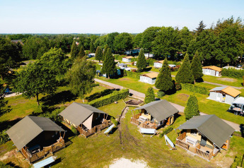 Vista aerea delle tende safari Villatent Outback e delle piazzole immerse nel verde al Camping de Schatberg, Paesi Bassi.