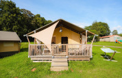 Tienda safari Villatent Outback en Camping La Colline, Bélgica, con porche de madera y hamaca exterior.