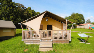 Safaritent Villatent Outback op Camping La Colline in België, met houten veranda en hangmat op grasveld.