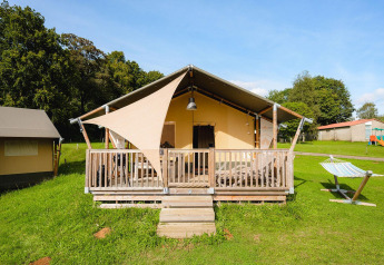 Safaritent Villatent Outback bij Camping La Colline in België, met houten terras en hangmat op het gras.