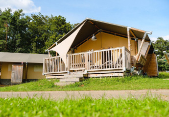 Safari-Zelt Villatent Outback auf Camping La Colline in Belgien mit Holzveranda und grüner Wiese.